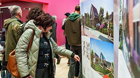 Een bezoeker bekijkt een paneel met een project op de Woonmarkt Nissewaard.