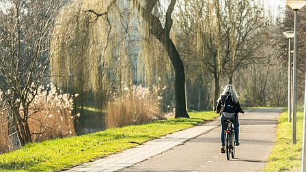 Fietser op fietspad met groen en water erlangs in de wijk Sterrenkwartier in Spijkenisse.