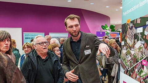 Bezoekers van de Woonmarkt Nissewaard bekijken een paneel met een impressie van een nieuwbouwproject.