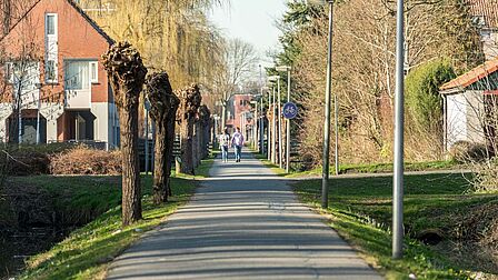 Wandelaars op een fietspad met veel groen erlangs in de wijk Sterrenkwartier in Spijkenisse. 