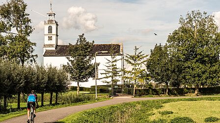 Het Witte Kerkje van Simonshaven, met lentegroen en een fietser.
