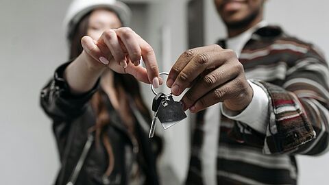 Jonge woningkopers laten de sleutel van hun nieuwe huis zien.