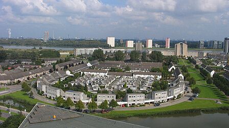 Luchtfoto van de wijk Schenkel in Spijkenisse. Aan de overkant van de Oude Maas de woontorens in Hoogvliet.