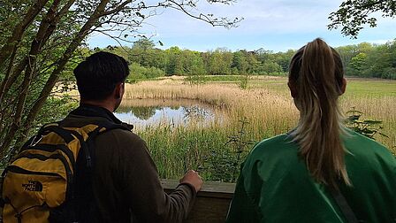 Twee natuurliefhebbers kijken uit over een duinplas.